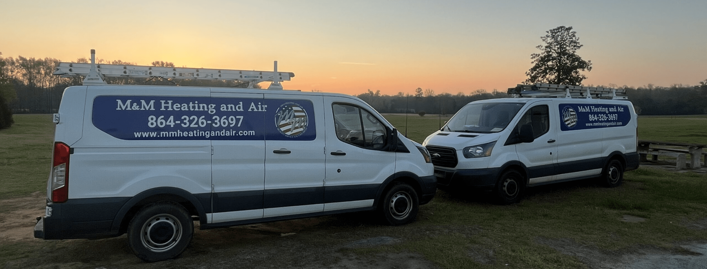 Two M&M Heating & Air trucks outside at sunrise - smaller photo.